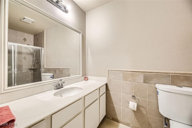 bathroom with vanity, toilet, tile walls, and walk in shower