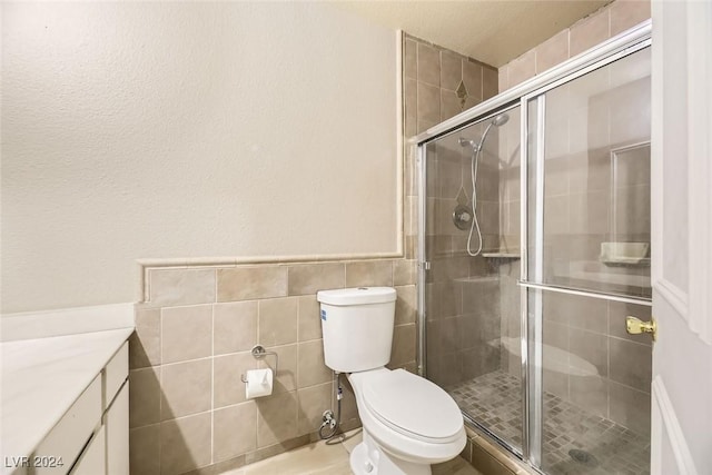 bathroom featuring vanity, toilet, tile walls, and a shower with shower door