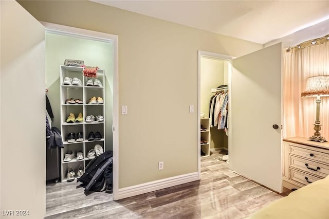 bedroom with a walk in closet, light hardwood / wood-style floors, and a closet