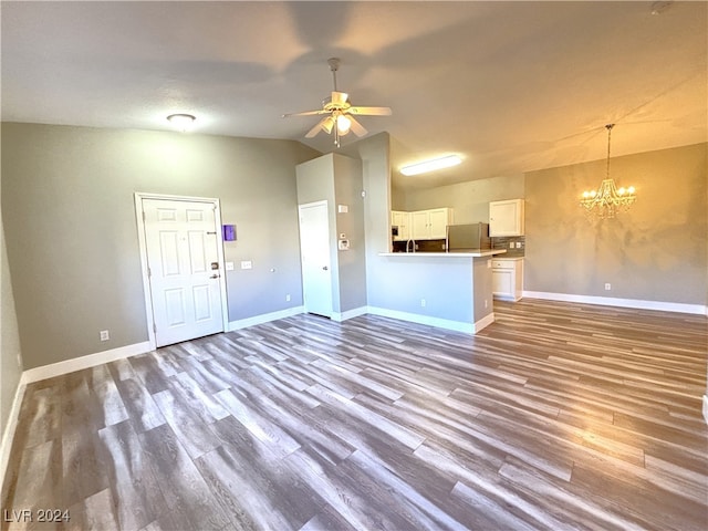 unfurnished living room with hardwood / wood-style floors, ceiling fan with notable chandelier, and lofted ceiling
