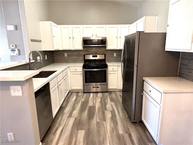 kitchen featuring dark wood-type flooring, sink, tasteful backsplash, white cabinetry, and stainless steel appliances