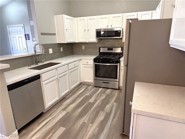 kitchen featuring sink, tasteful backsplash, wood-type flooring, white cabinets, and appliances with stainless steel finishes