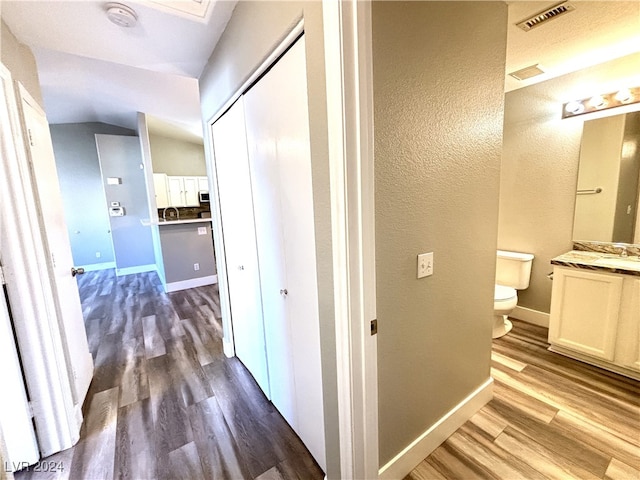 hall featuring dark hardwood / wood-style flooring, lofted ceiling, and sink