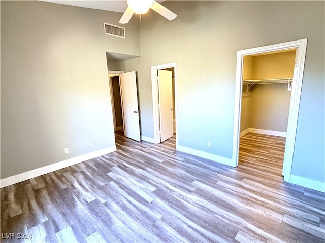 unfurnished bedroom with a towering ceiling, light wood-type flooring, and ceiling fan