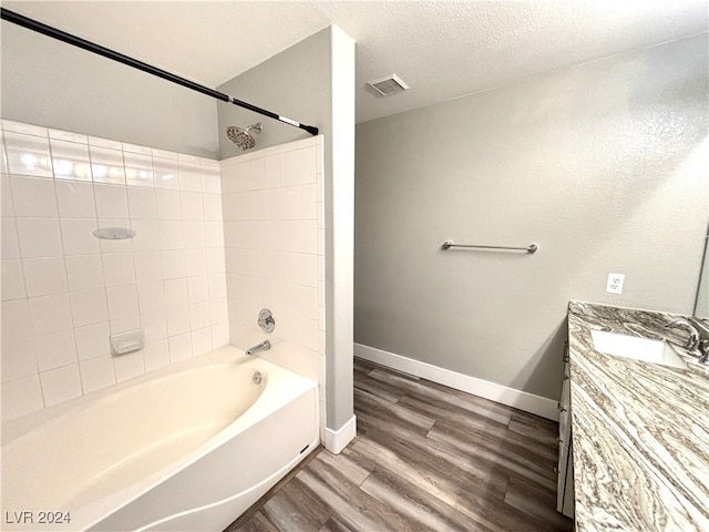 bathroom with vanity, tiled shower / bath, a textured ceiling, and hardwood / wood-style flooring