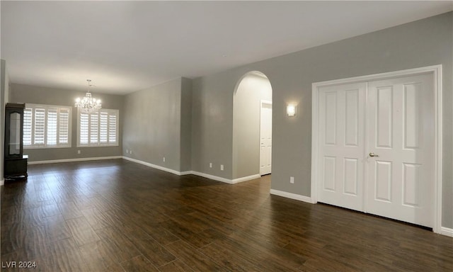 spare room featuring dark hardwood / wood-style floors and an inviting chandelier