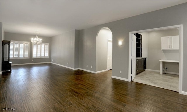 unfurnished living room featuring dark wood-type flooring and a notable chandelier