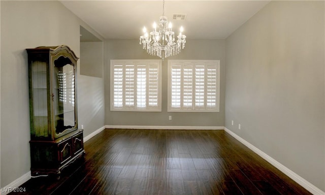 unfurnished dining area with dark wood-type flooring and a notable chandelier