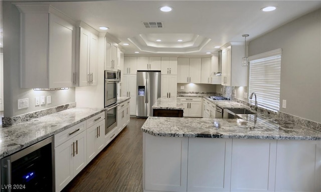 kitchen with hanging light fixtures, sink, white cabinetry, stainless steel appliances, and beverage cooler