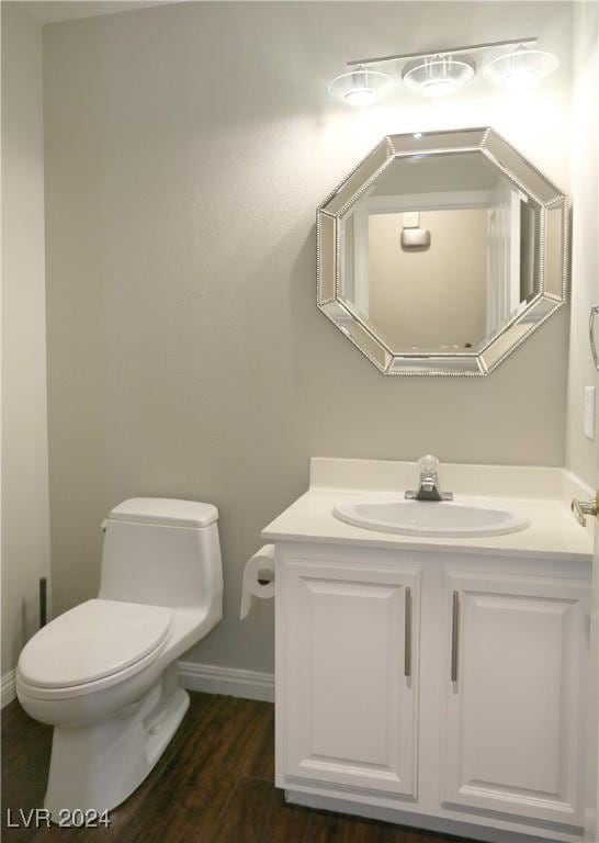 bathroom with hardwood / wood-style floors, vanity, and toilet