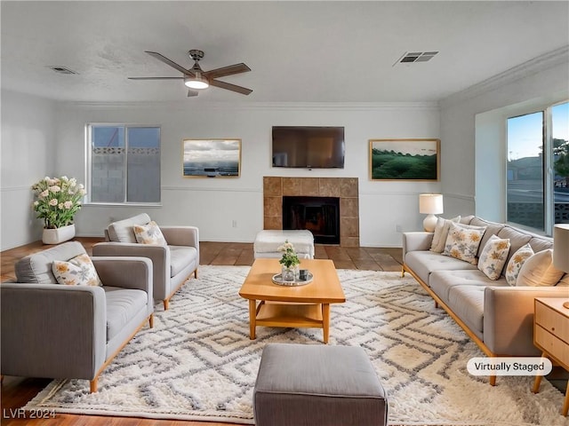 living room featuring a tile fireplace, light wood-type flooring, and ornamental molding