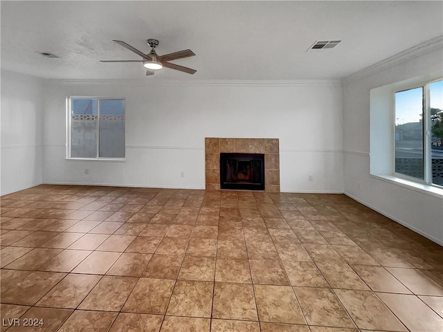 unfurnished living room with a tiled fireplace, ceiling fan, and ornamental molding