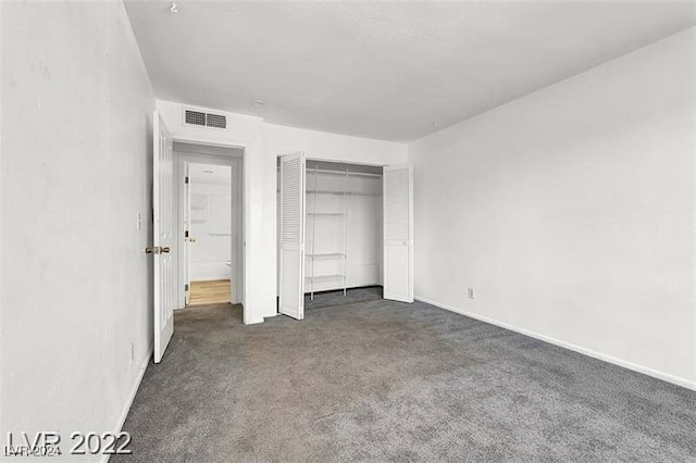 unfurnished bedroom with a closet and dark colored carpet