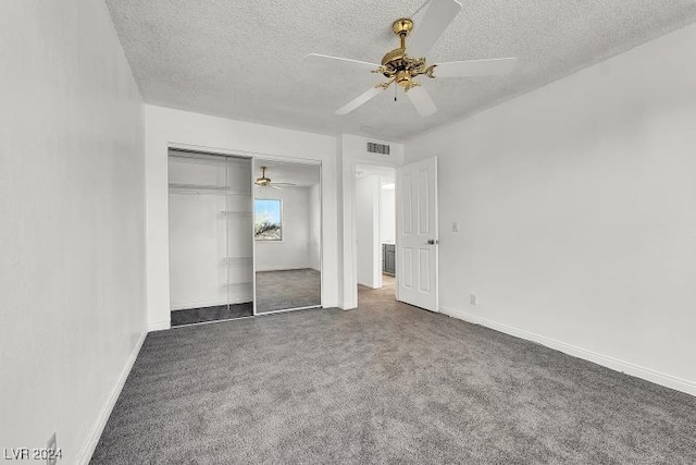 unfurnished bedroom featuring dark colored carpet, a textured ceiling, a closet, and ceiling fan