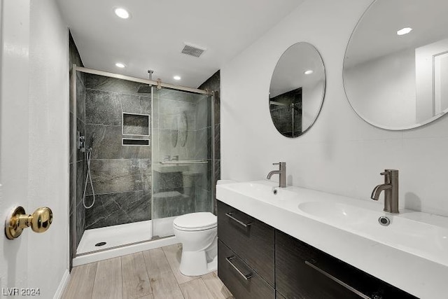 bathroom featuring hardwood / wood-style floors, vanity, a shower with door, and toilet