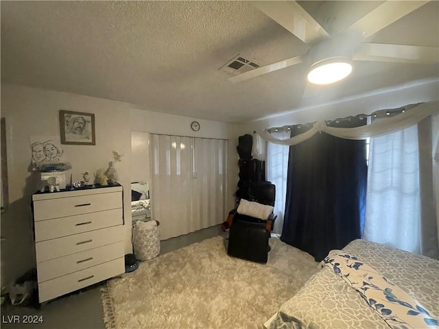 carpeted bedroom featuring ceiling fan and a textured ceiling