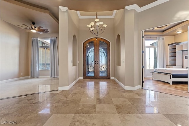 foyer with french doors, a towering ceiling, ceiling fan with notable chandelier, and ornamental molding