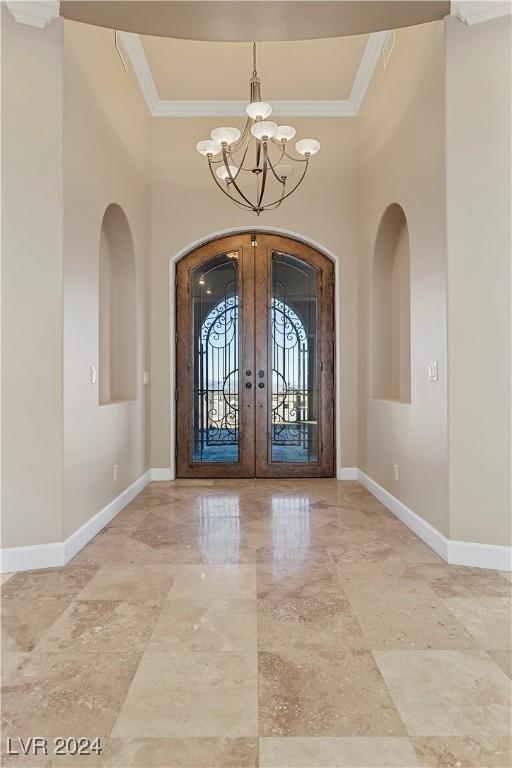 entryway with french doors, ornamental molding, and a notable chandelier