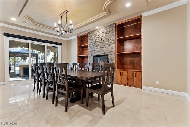 dining space featuring a raised ceiling, built in shelves, a fireplace, and ornamental molding