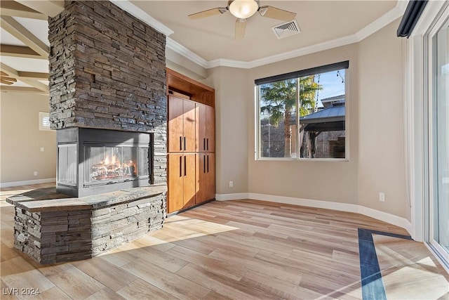 unfurnished living room with ceiling fan, light hardwood / wood-style floors, a stone fireplace, and ornamental molding