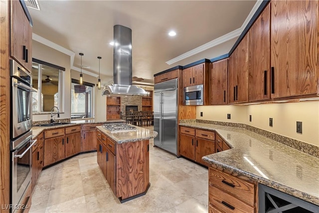 kitchen with a center island, sink, built in appliances, decorative light fixtures, and island range hood