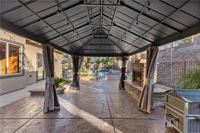 view of patio with a gazebo and an outdoor stone fireplace