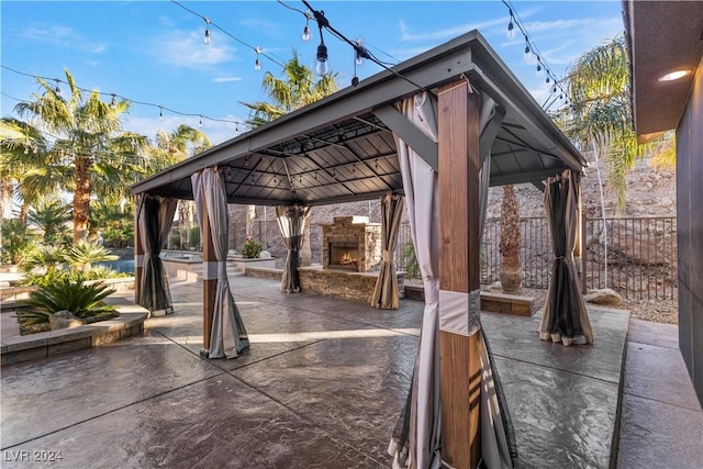 view of patio / terrace featuring a gazebo and an outdoor stone fireplace