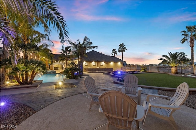 patio terrace at dusk featuring a lawn and pool water feature