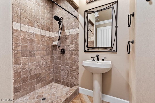 bathroom featuring sink, ornamental molding, and tiled shower