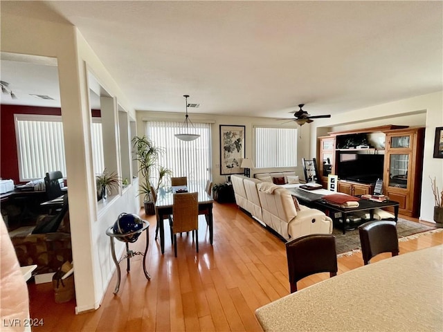 living room with light wood-type flooring, ceiling fan, and a healthy amount of sunlight