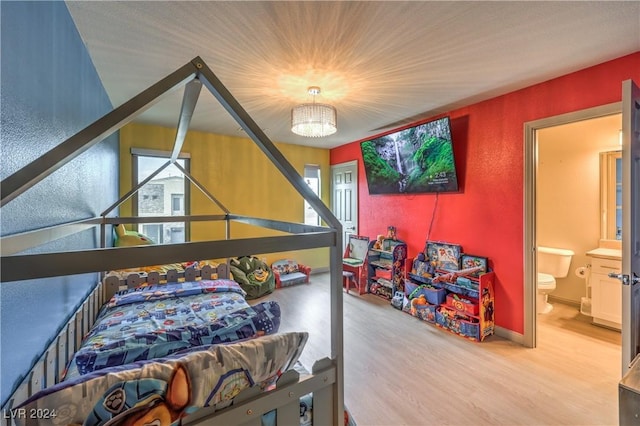 interior space with a chandelier, ensuite bathroom, and wood-type flooring