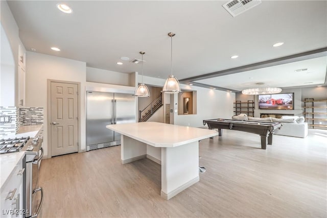 kitchen featuring billiards, decorative light fixtures, a breakfast bar, a kitchen island, and high end appliances