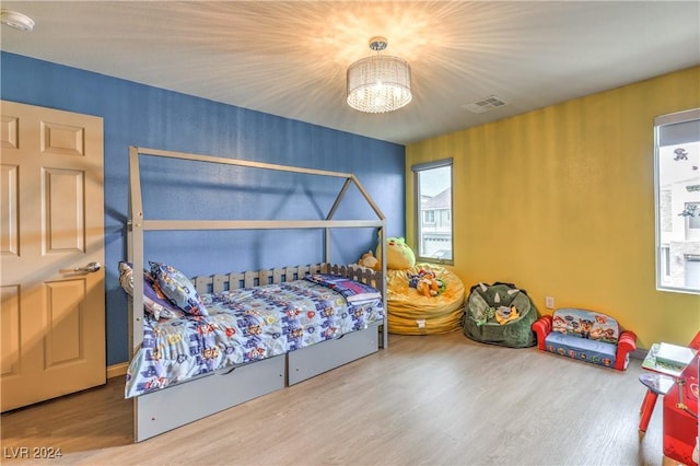 bedroom with multiple windows, hardwood / wood-style floors, and a notable chandelier