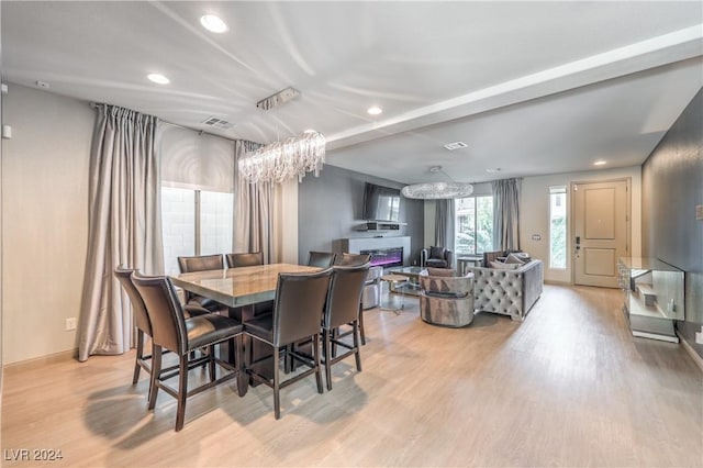 dining area featuring light wood-type flooring and a notable chandelier