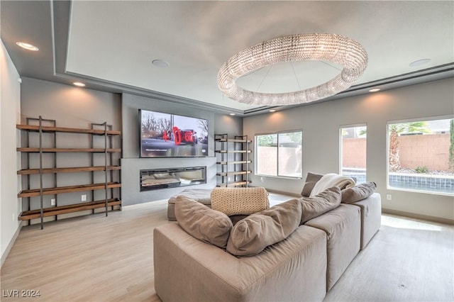 cinema featuring a chandelier, a tray ceiling, and light hardwood / wood-style flooring