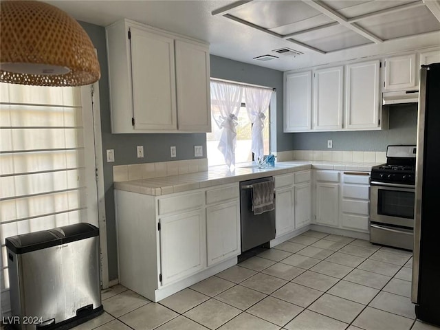 kitchen with tile counters, light tile patterned floors, ventilation hood, white cabinets, and appliances with stainless steel finishes