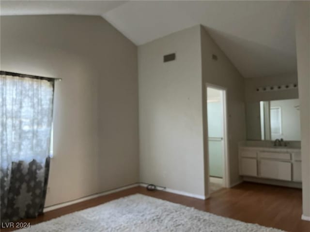 unfurnished bedroom with hardwood / wood-style floors, multiple windows, lofted ceiling, and sink