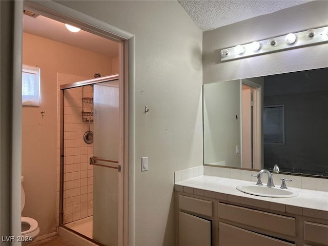 bathroom with vanity, a textured ceiling, toilet, and a shower with door