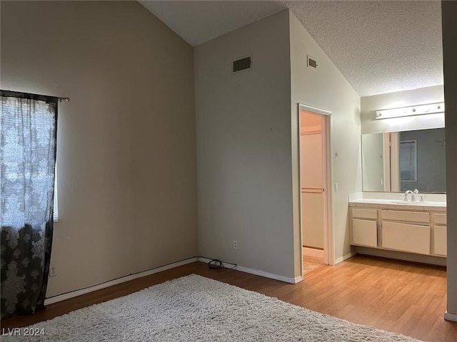 bathroom featuring hardwood / wood-style floors, vanity, a textured ceiling, and high vaulted ceiling