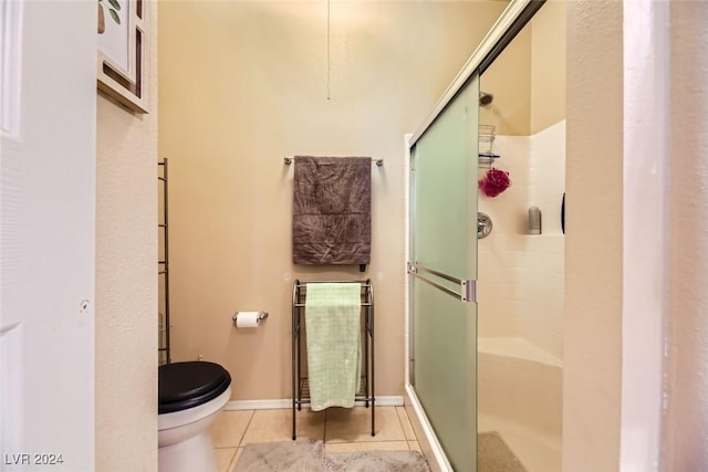 bathroom featuring tile patterned flooring, toilet, and a shower with shower door