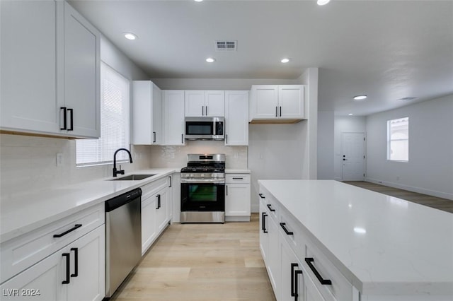 kitchen with a healthy amount of sunlight, white cabinetry, sink, and appliances with stainless steel finishes