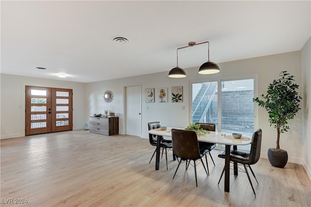 dining area with french doors and light hardwood / wood-style flooring