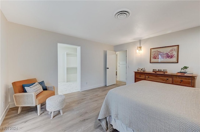 bedroom with light hardwood / wood-style floors and a spacious closet