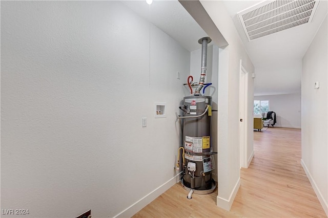 corridor with water heater and light hardwood / wood-style floors