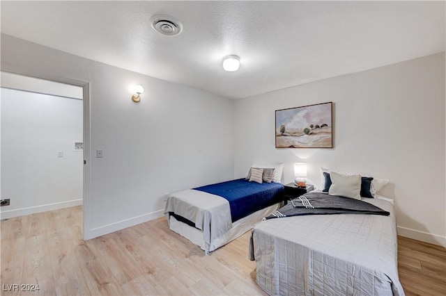 bedroom featuring light hardwood / wood-style flooring and a textured ceiling