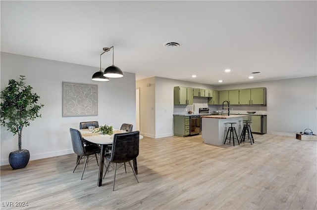 dining space with wine cooler, sink, and light wood-type flooring