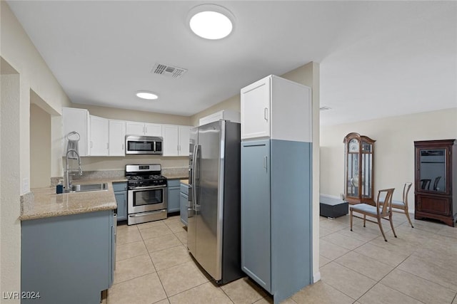 kitchen with white cabinets, sink, light stone countertops, light tile patterned floors, and appliances with stainless steel finishes