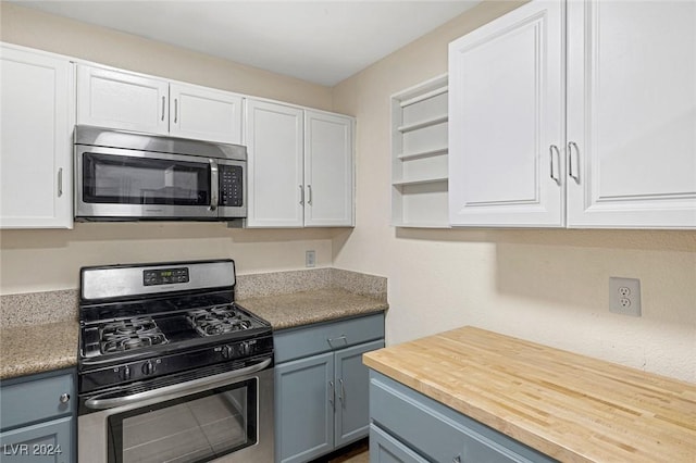 kitchen with butcher block counters, white cabinets, gray cabinetry, and appliances with stainless steel finishes