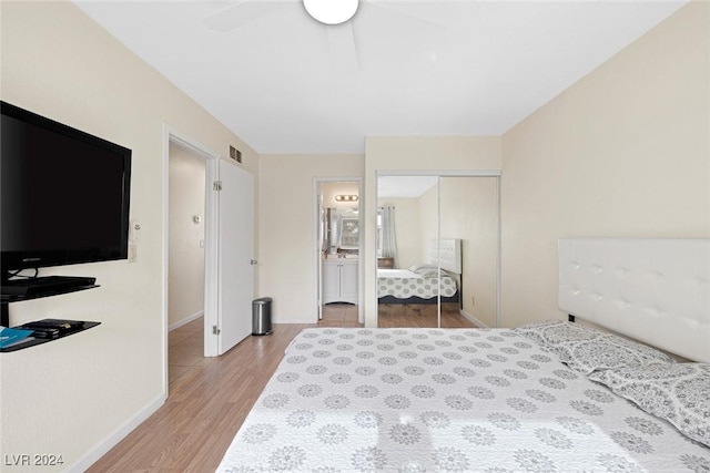 bedroom with ceiling fan, light hardwood / wood-style floors, ensuite bathroom, and a closet