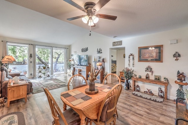 dining area with a textured ceiling, light wood-type flooring, vaulted ceiling, and ceiling fan